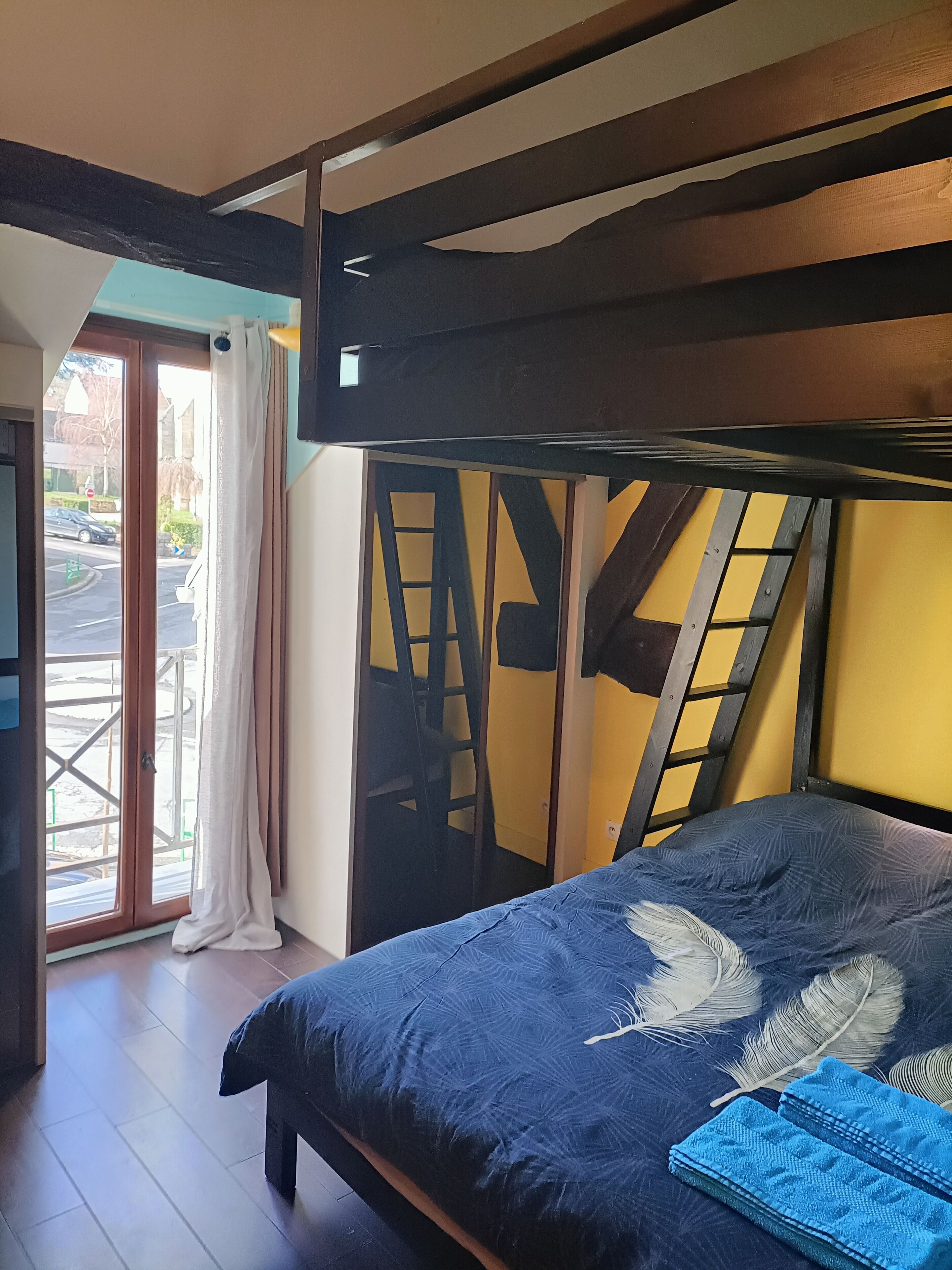 Ein Zimmer mit Etagenbett, Blick durch eine Glastür und einer gelben Wand.