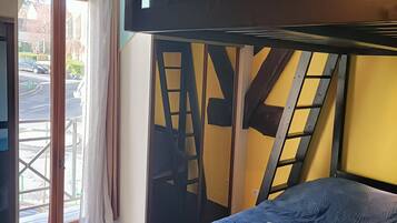Ein Zimmer mit Etagenbett, Blick durch eine Glastür und einer gelben Wand.