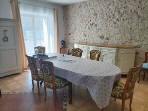 Ein Essbereich mit einem Tisch, der mit einer gemusterten Tischdecke bedeckt ist, umgeben von verzierten Stühlen.