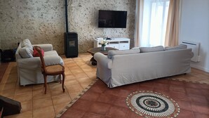 Un salon avec un canapé, un fauteuil, une télévision et une cheminée.