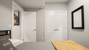Un dormitorio con cama, mesita de noche, armario y un cuadro en la pared.