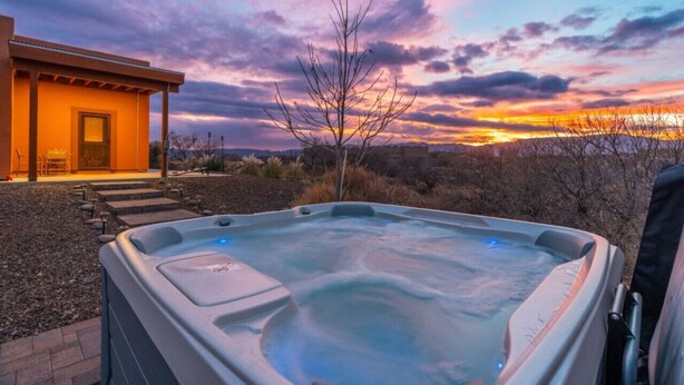 A hot tub in a landscaped area with a building in the background. - Terracotta Cove - Hot tub, Fire pit, Stargazing (Cornville)
