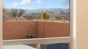 A dining area with a table set for two, a window with a view of a desert landscape, and a plant on the windowsill. - Terracotta Cove - Hot tub, Fire pit, Stargazing (Cornville)