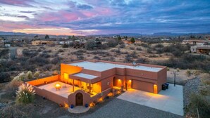 A modern building with a flat roof, a patio area, and a well-lit interior. - Terracotta Cove - Hot tub, Fire pit, Stargazing (Cornville)