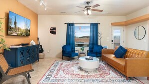 A living room with a blue sofa, a brown sofa, a coffee table, and a TV on the wall. - Terracotta Cove - Hot tub, Fire pit, Stargazing (Cornville)