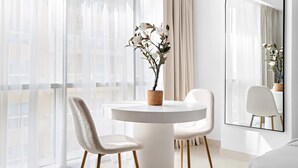 A modern room with a round white table, two chairs, a potted plant, and a large mirror. - Silkhaus Nova Tower DSO (Dubai)
