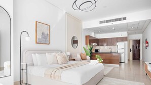 A modern hotel room with a large bed, bedside tables, a desk, and a view into the kitchen area. - Silkhaus Nova Tower DSO (Dubai)