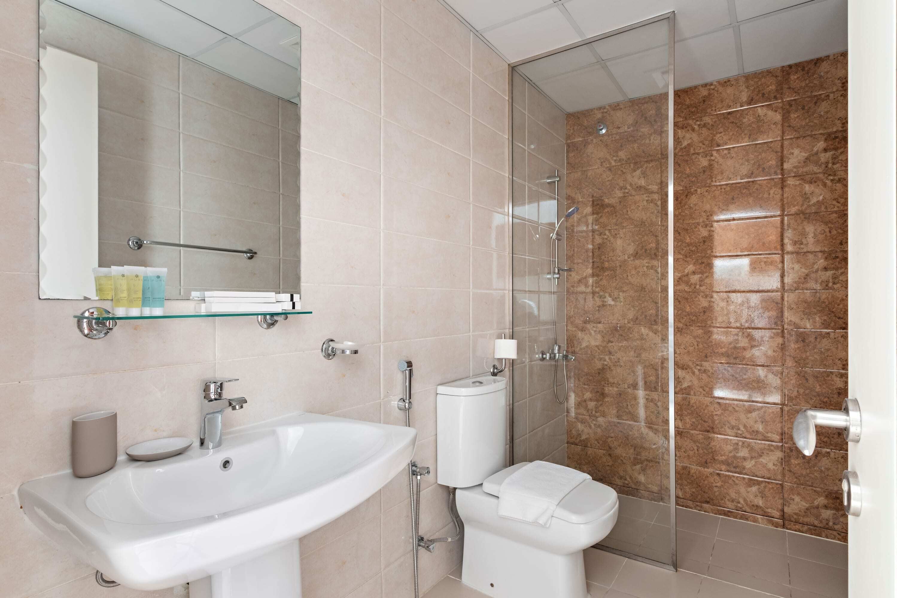A modern bathroom with a sink, toilet, and glass shower enclosure.