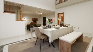 Un coin repas avec une table dressée pour quatre personnes, un banc et un escalier menant à un niveau supérieur.