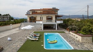 Une maison à deux étages dotée d’une piscine, d’un espace extérieur aménagé et offrant une vue sur les montagnes.