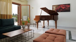 Un salon comprenant un grand piano, un canapé, une table basse et un tableau accroché au mur.