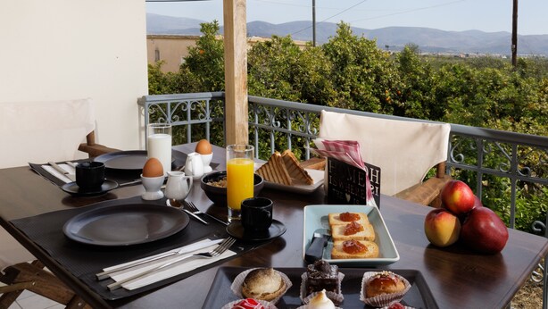 Une table de petit-déjeuner avec des viennoiseries, un verre de jus d’orange et une vue sur la campagne.