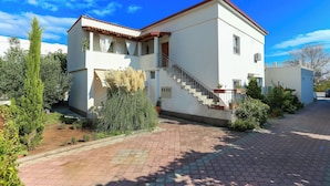 A two-story building with a red-tiled roof, a staircase leading to the upper floor, and a paved driveway. - Room-apartments & Rooms Buble - Studio w (Trogir)