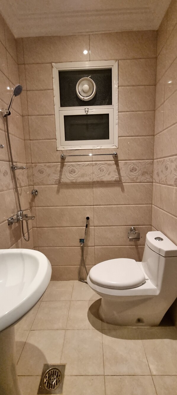Un baño con inodoro, bidé y ducha con cabezal de ducha manual.