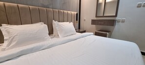 Una cama bien hecha con sábanas blancas y un cabecero acolchado.