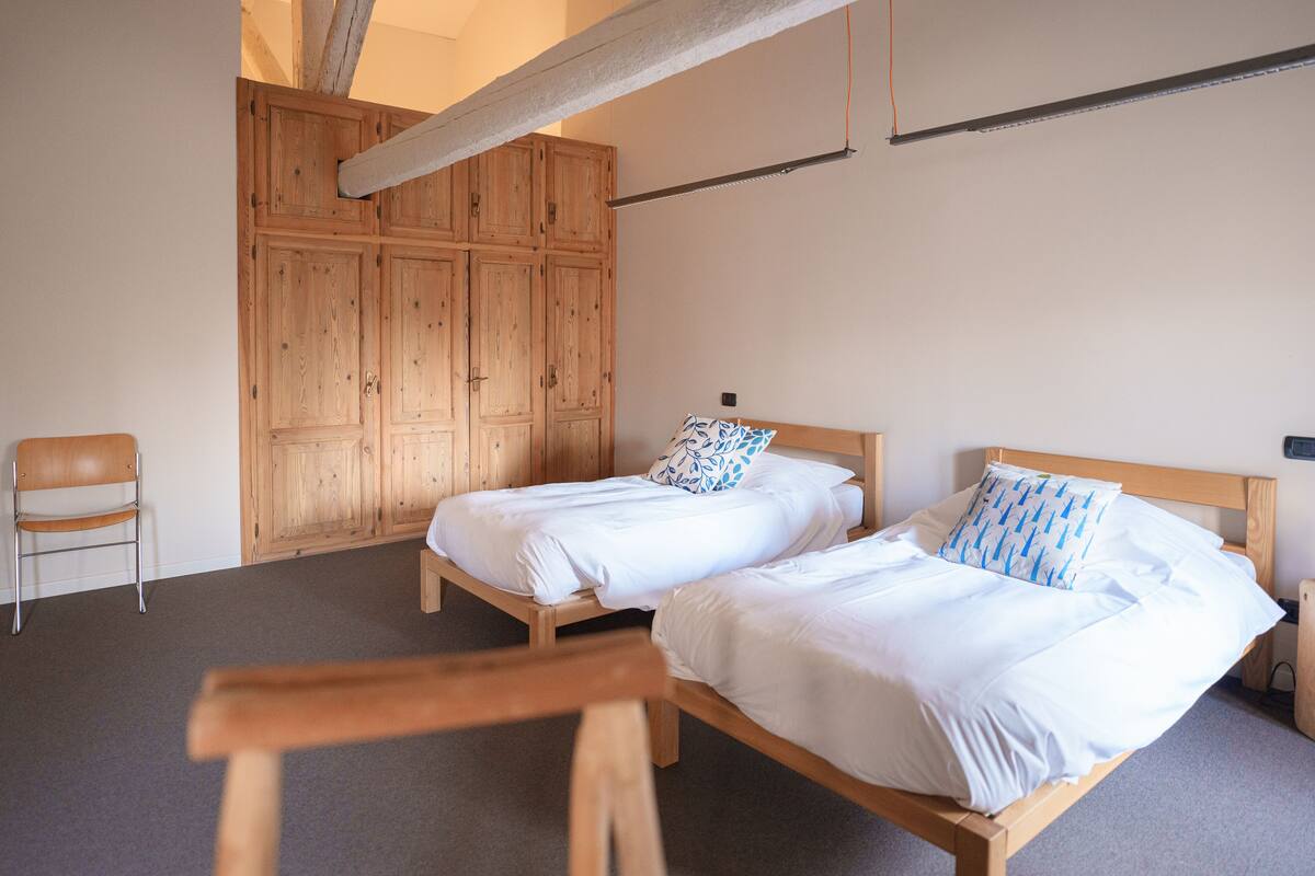 A room with two wooden beds, a wooden chair, and a large wooden wardrobe.
