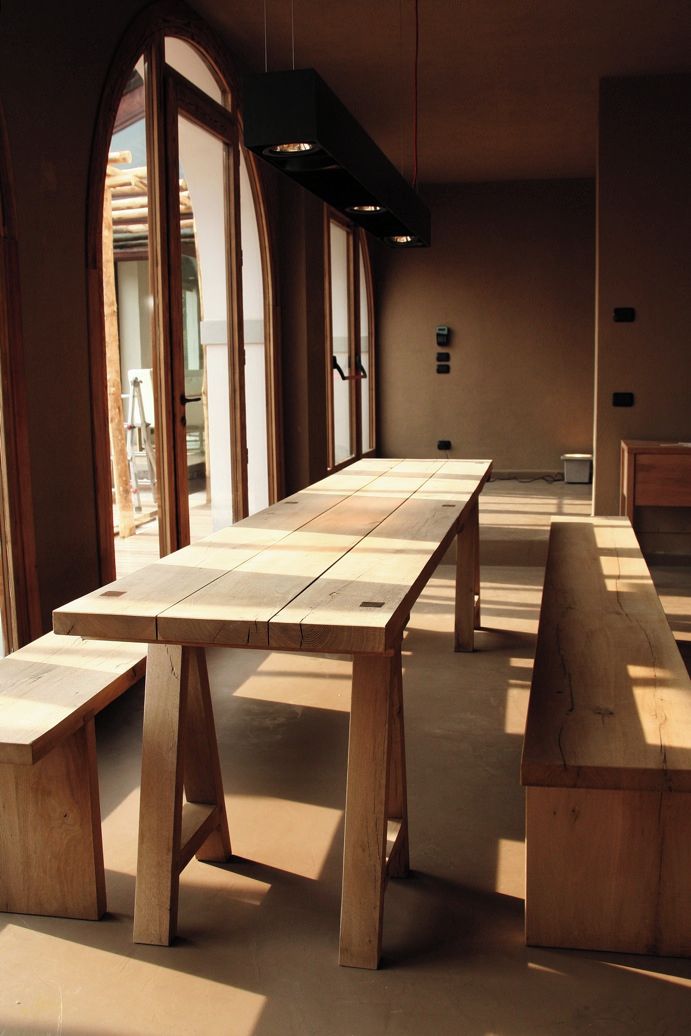 Una habitación con una larga mesa de madera, bancos y una lámpara colgante.