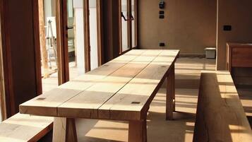 Una habitación con una larga mesa de madera, bancos y una lámpara colgante.