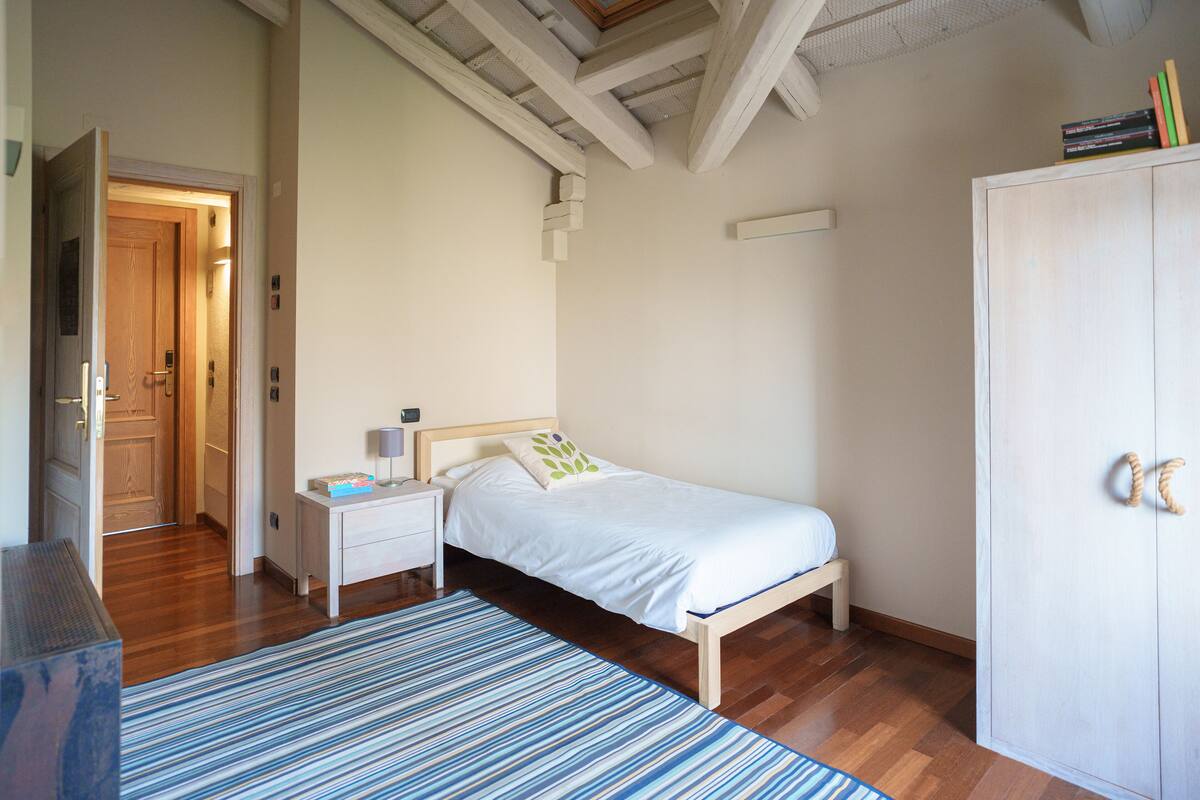 A bedroom with a bed, nightstand, and wardrobe.