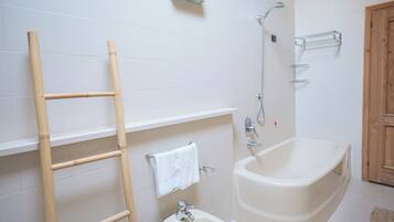 Ein Badezimmer mit einer Badewanne, einer Dusche, einer Toilette und einem Handtuchhalter.