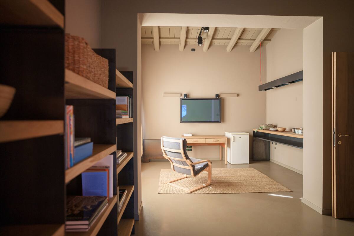 A modern kitchen with a built-in oven, a small refrigerator, and a wooden countertop.