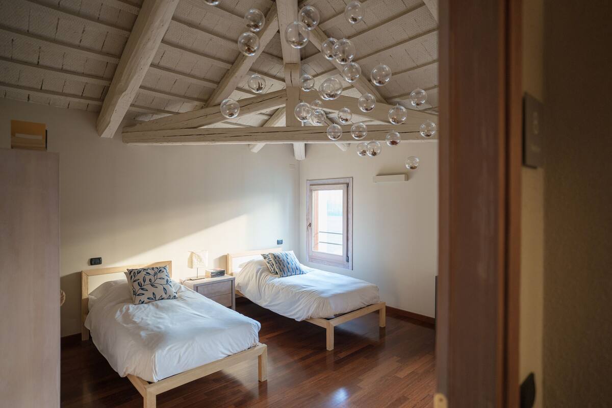 A bedroom with two beds, wooden beams, a window, and a ceiling with bubbles.