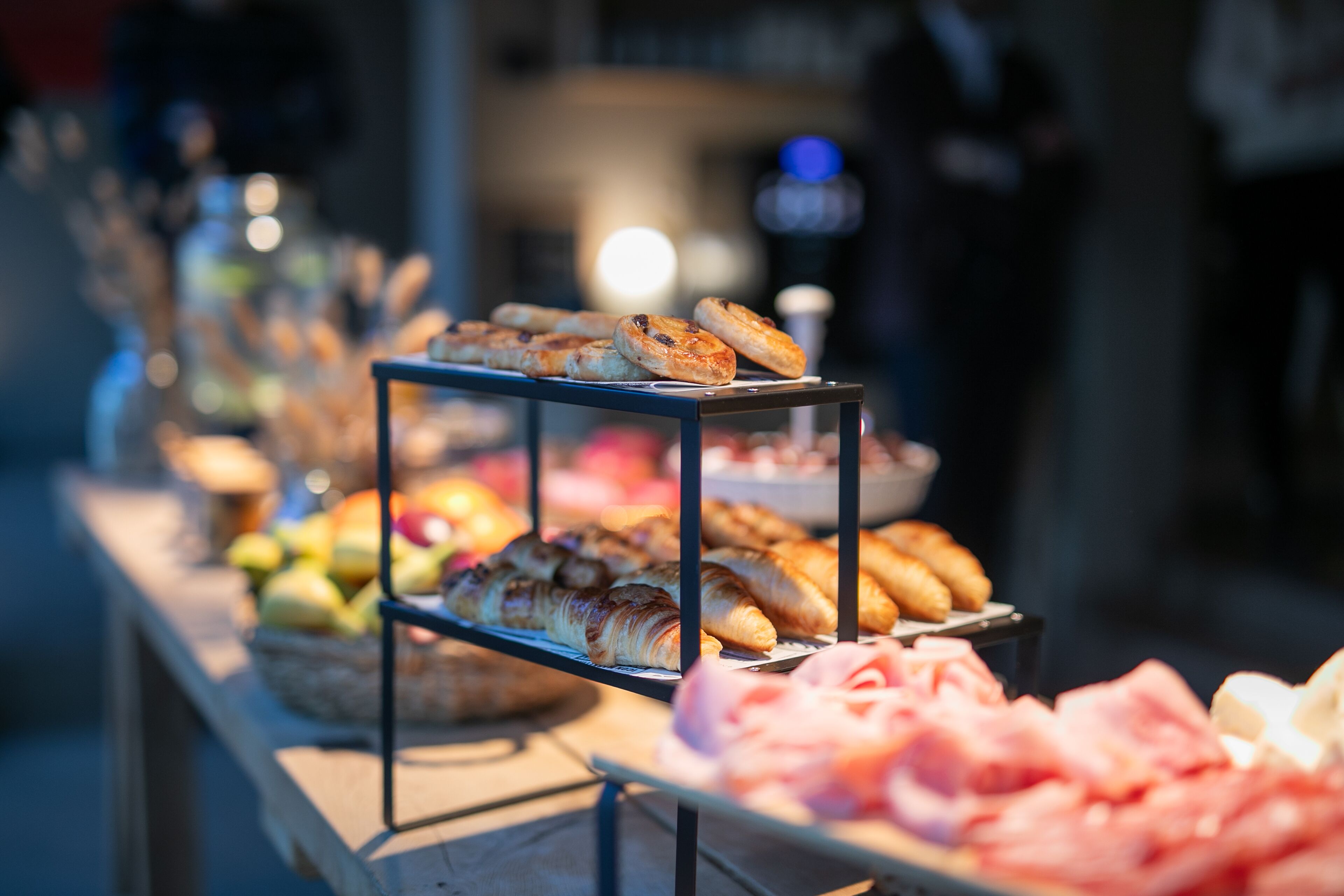 Een buffet met diverse gerechten, waaronder gebak, vleeswaren en fruit.