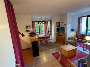 A living room with a television, a dining table, and a sofa. - 2-room apartment near slopes, balcony, sleeps 4-6 (Villard-de-Lans)