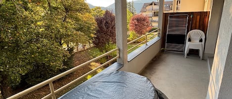 A balcony with a view of trees and a distant mountain.