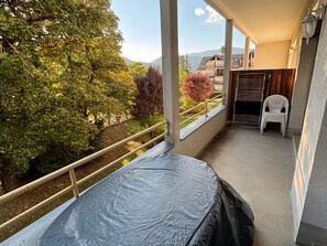 Un balcon avec vue sur les arbres et une montagne lointaine.