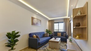 Ein modernes Wohnzimmer mit einem blauen Sofa, einem Couchtisch und einer Topfpflanze.