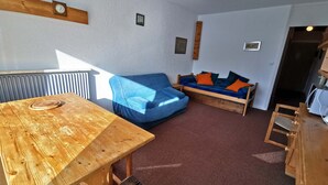Une pièce chaleureuse avec une table en bois, un canapé bleu et un lit en bois.