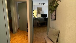 En hall som leder till ett vardagsrum med en soffa, en tv och en växt.