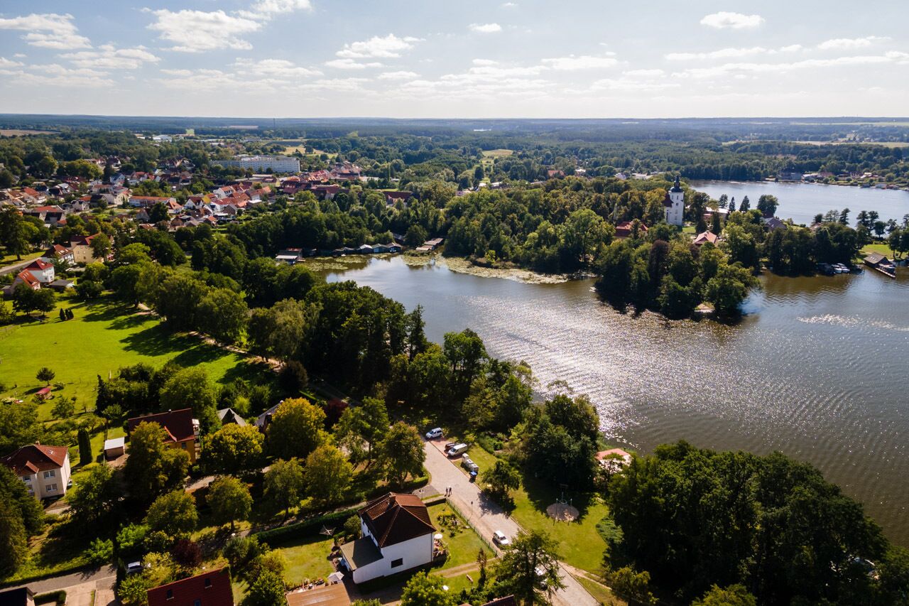 An aerial view of a lakeside town with residential buildings, a church, and a clear sky.