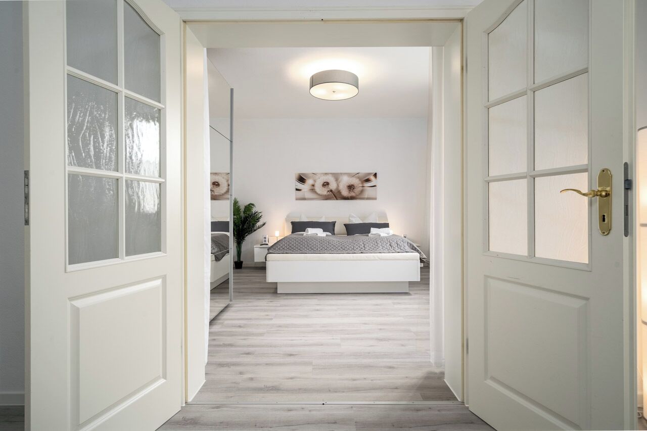 A bedroom with a bed, nightstands, and wall art.
