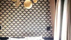 Ein Bett mit einem gemusterten Kopfteil und einem Fenster mit Vorhängen.