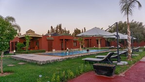 Un hotel con piscina, mobiliario exterior y un jardín bien cuidado.