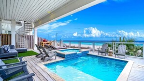 Ein Poolbereich mit Liegestühlen, einem Whirlpool und Blick auf den Strand.