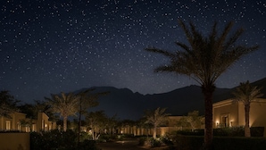 A starry night sky over a resort with palm trees and buildings. - Naama Beach Villas & Spa (Al Aqah)