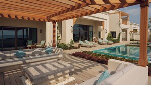 Ein moderner Außenbereich mit Pool, Holz-Pergola und Gartenmöbeln.