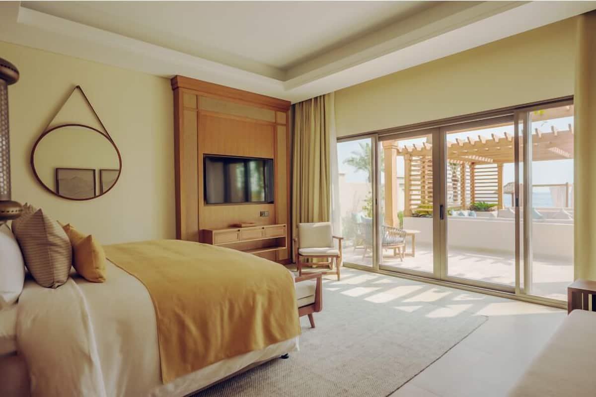Ein Hotelzimmer mit Bett, Fernseher, Stuhl und einer Glastür zu einem Außenbereich.