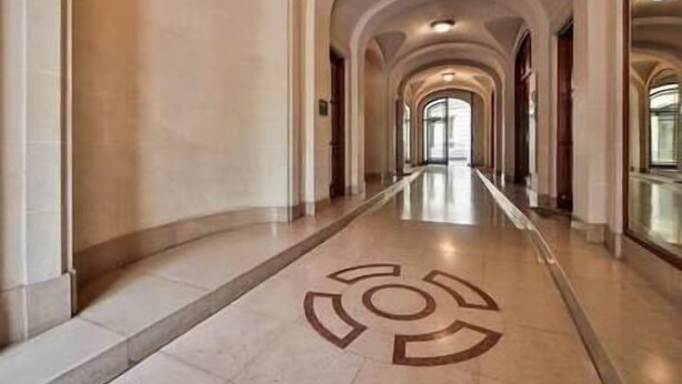 A long, arched hallway with a marble floor and a circular emblem in the center.