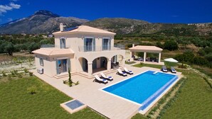 A two-story villa with a swimming pool, outdoor seating, and a mountainous backdrop. - Villa Aglaia in Mavrata (Kefalonia)