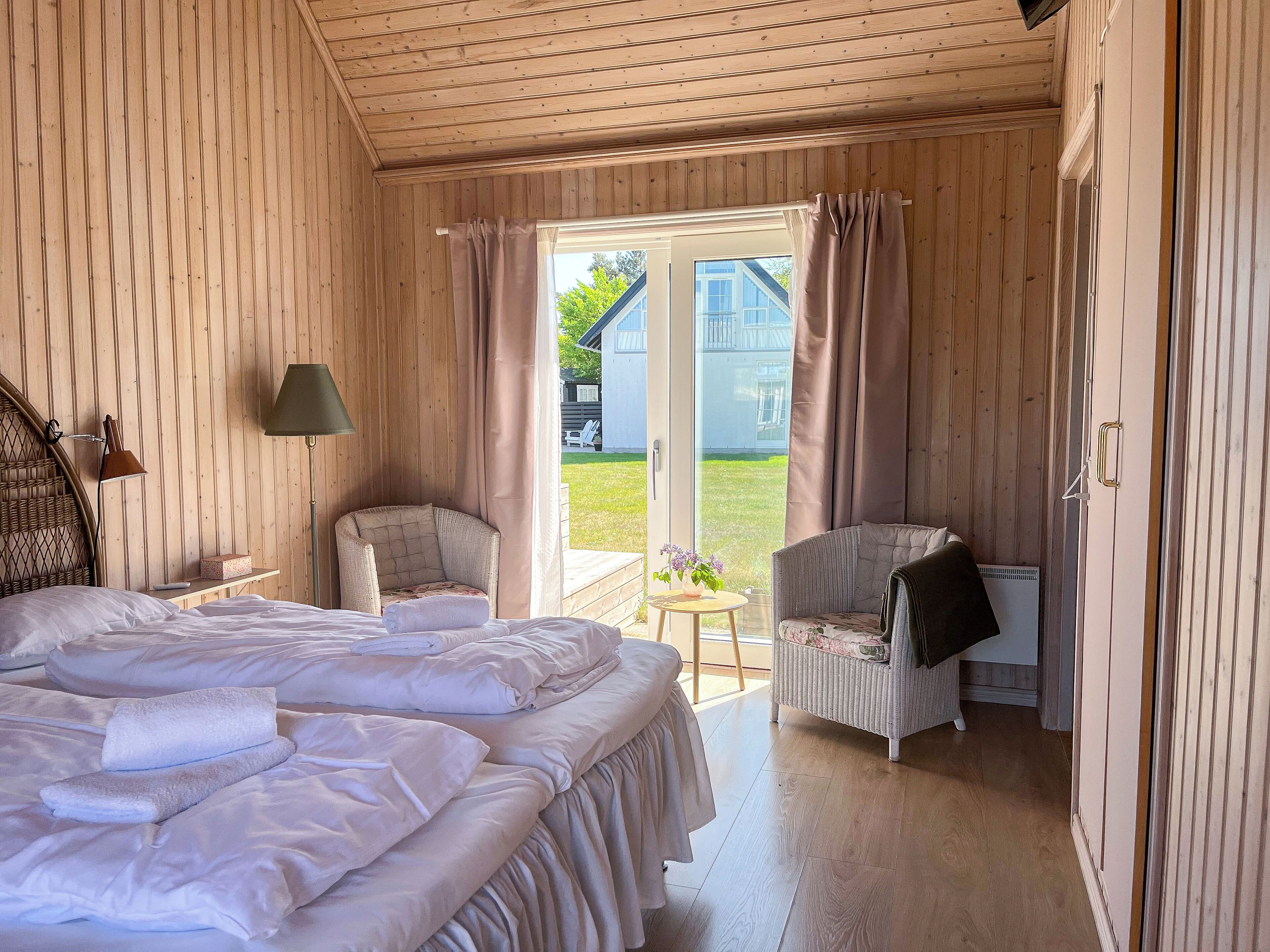 Una habitación acogedora con una cama, dos sillas, una mesa y una puerta que da a un balcón.