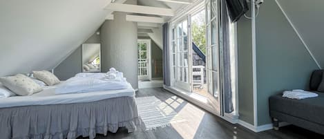 Un dormitorio con una cama grande, un sofá y vistas amplias por un ventanal.