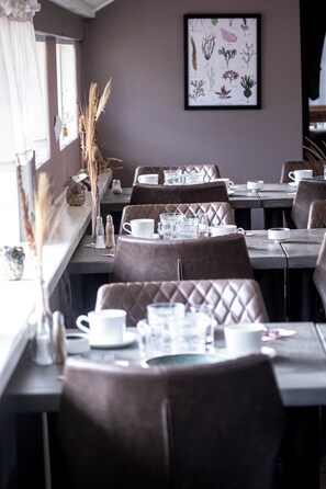 A restaurant with a long counter, cushioned booths, and a framed botanical illustration on the wall.