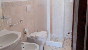 Une salle de bain équipée de toilettes, d’un bidet et d’un lavabo.