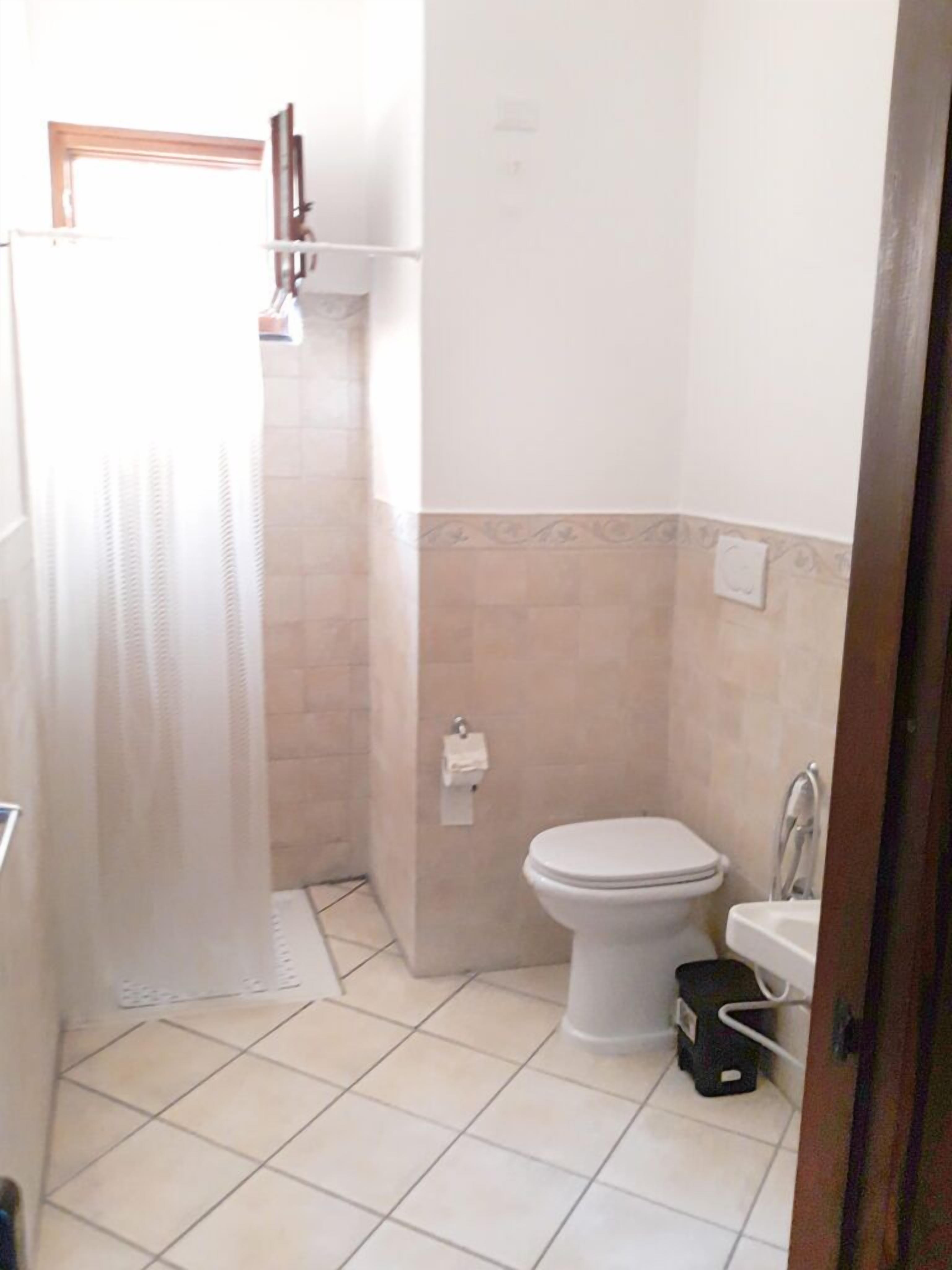 Baño pequeño con inodoro, lavamanos y zona de ducha.