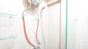 Een douche met een handdouche en een bedieningspaneel aan de muur.
