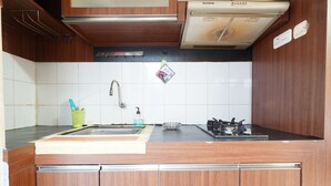 Een keuken met houten kastjes, een roestvrijstalen spoelbak, een gasfornuis en een magnetron.